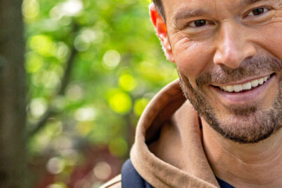 Mies katsoo kameraan ja hymyilee.