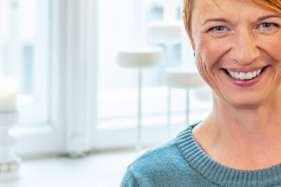 Punahiuksinen nainen katsoo kameraan ja hymyilee.