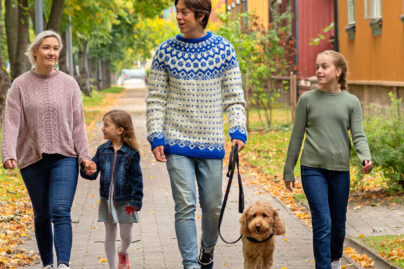 Perhe kävelee ulkona puutaloalueella.