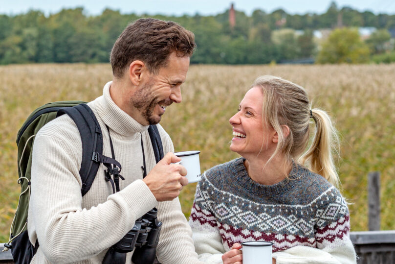 Mies ja nainen ulkona hymyilevät toisilleen.