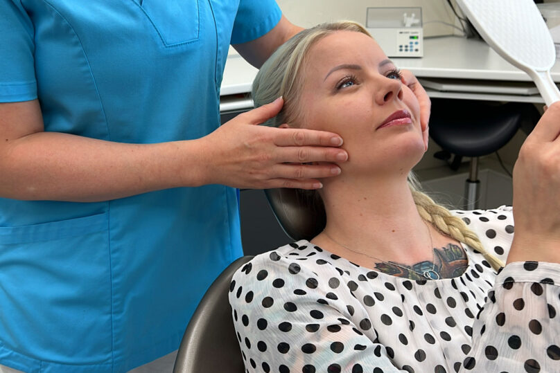 asiakas hymyilee ja katsoo peiliin hammaslääkärin tuolissa