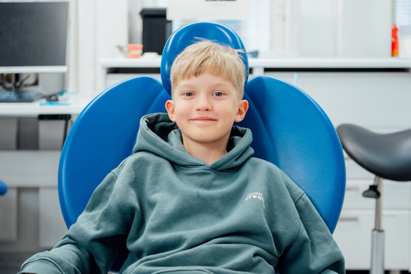 Lasten oikomishoito - poika istuu hammaslääkärin tuolissa hymyillen.