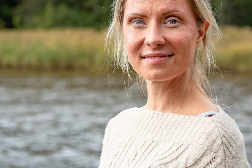 Vaaleahiuksinen nainen ulkona hymyilee kevyesti