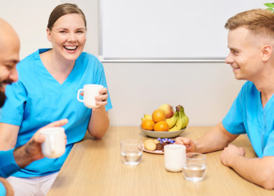 hoitajat ja hammaslääkäri istuvat kahvihuoneen pöydän ääressä juttelemassa