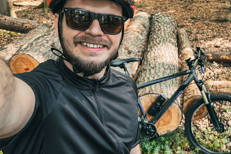 Tules-kuntoutuskurssille osallistuva mies pyöräilemässä maastossa ja ottamassa itsestä kuvaa pyörän kanssa