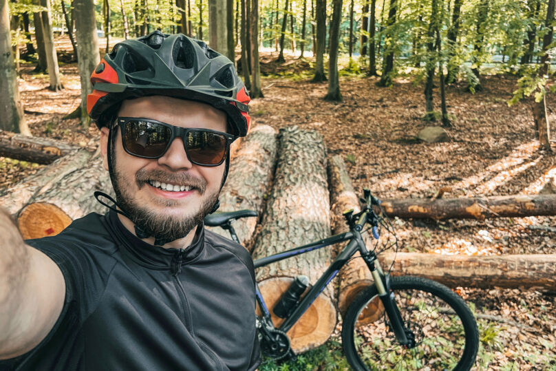 Tules-kuntoutuskurssille osallistuva mies pyöräilemässä maastossa ja ottamassa itsestä kuvaa pyörän kanssa