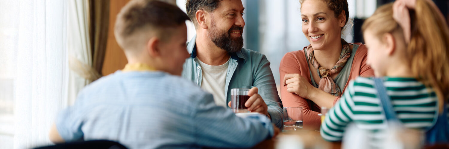 Nelihenkinen perhe syömässä yhdessä ravintolassa.