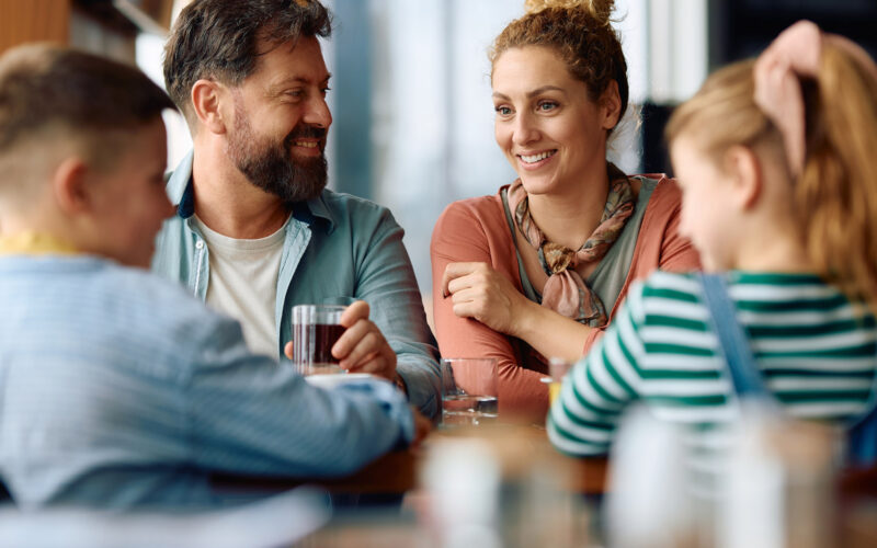 Nelihenkinen perhe syömässä yhdessä ravintolassa.