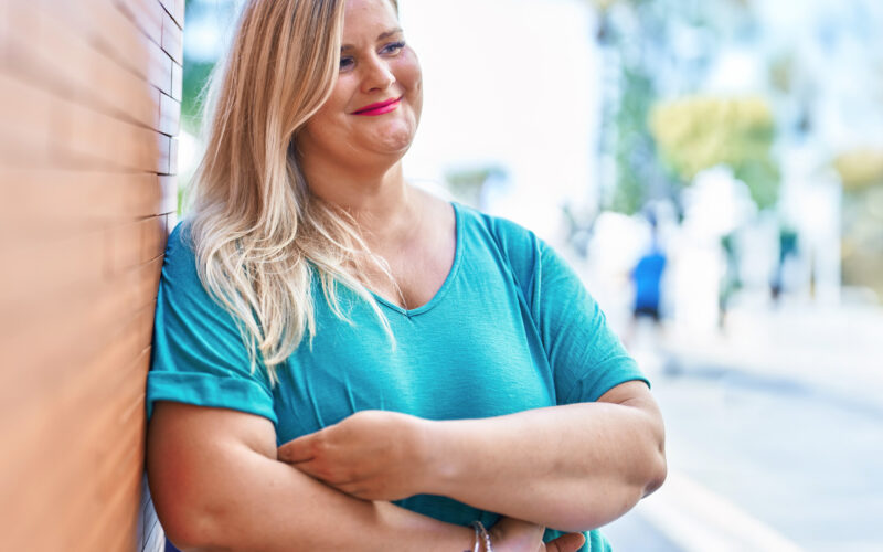 Neurologisten sairauksien moniammatillisen yksilökuntoutuksen asiakas ulkoilee ja nojailee talon seinään iloisena