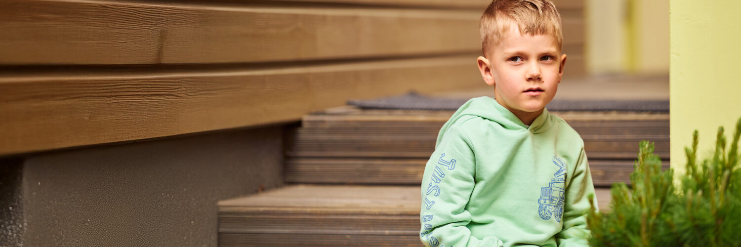 Poika istuu portailla Coronaria sopeutumisvalmennus lasten kielihäiriö