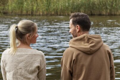 Nainen ja mies istuvat laiturilla ja katsovat toisiaan