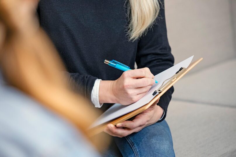 Lähikuva naisen käsistä kirjoittamassa muistiinpanojal