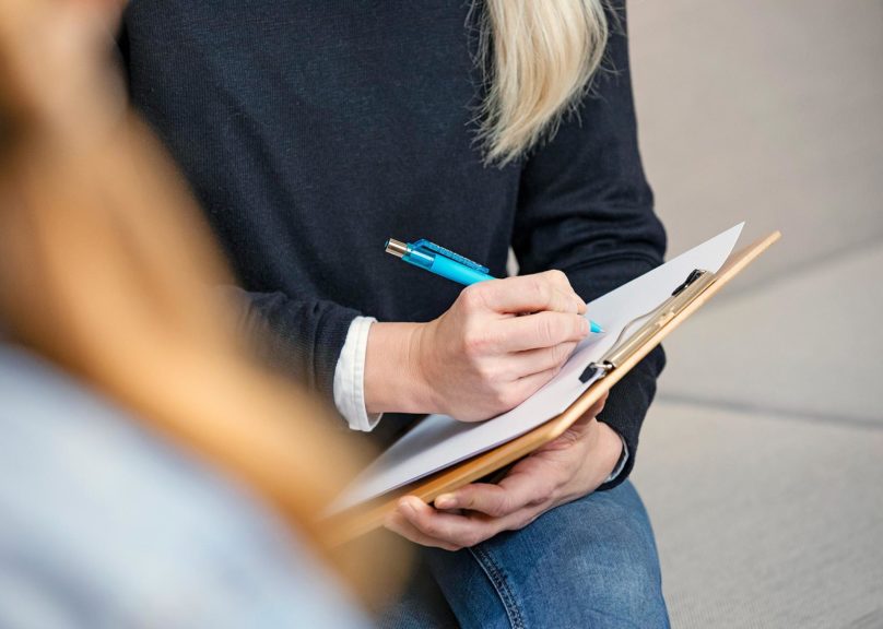 Lähikuva naisen käsistä kirjoittamassa muistiinpanojal