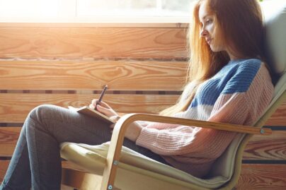 nuori nainen istuu tuolissa ja tekee muistiinpanoja