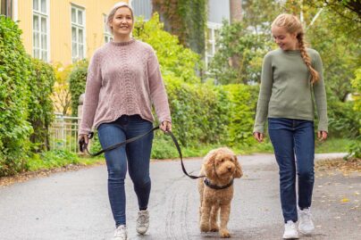 nainen ja tytto kavelevat koiran kanssa ulkona