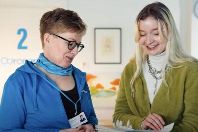 Oma Väylä -kuntoutuksen työntekijä Ruut ja asiakas Pinja katsovat yhdessä kirjaa.