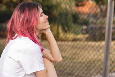 Nuori nainen istuu ulkona penkillä