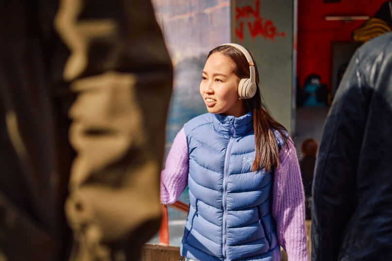 nuori nainen kävelee ulkona kuulokkeet päässä