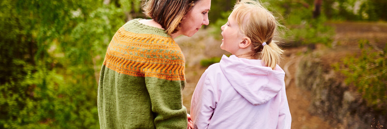 Aikuinen ja lapsi istuvat ulkona vierekkäin Coronaria sopeutumisvalmennus lapsen autismi