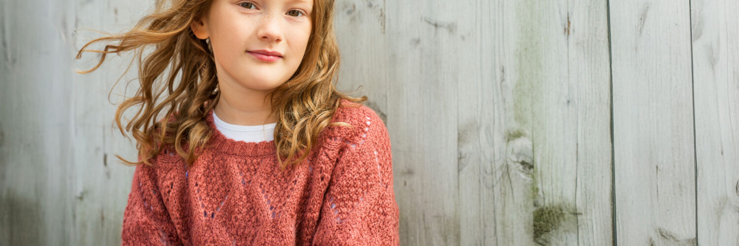 tyttö hymyilee harmaan lankkuseinän edessä Coronaria sopeutumisvalmennus ADHD ADD lapsille