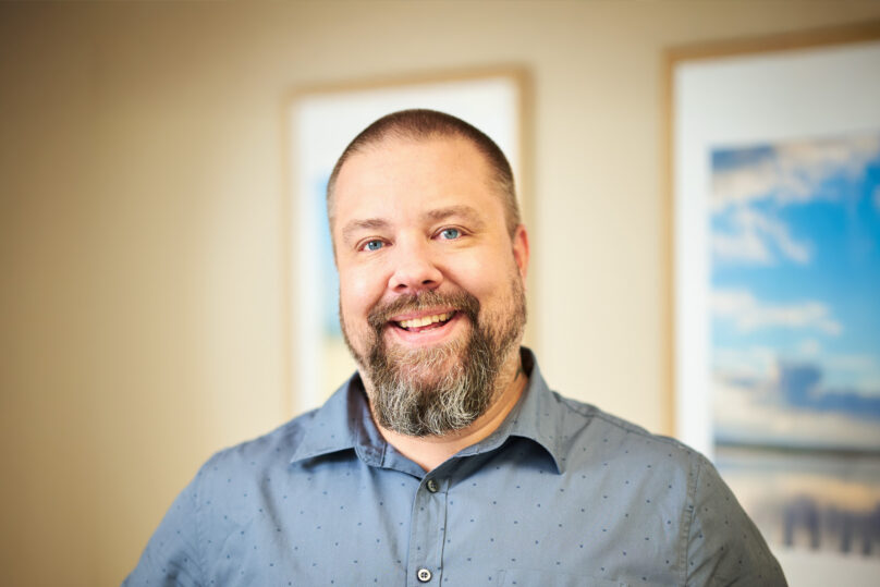 Aikuispsykiatri katsoo kameraan ja hymyilee.