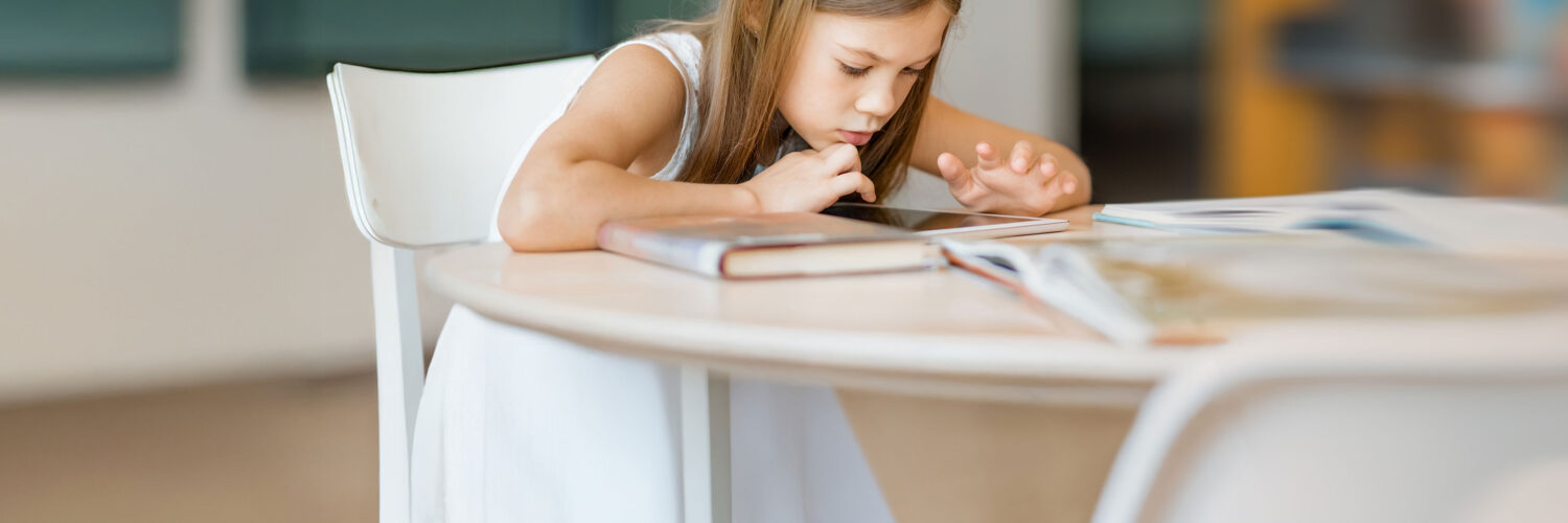 Tyttö lukee kirjaa pöydän ääressä Coronaria psykiatrin vastaanotto lapsille