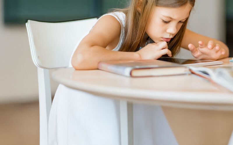 Tyttö lukee kirjaa pöydän ääressä Coronaria psykiatrin vastaanotto lapsille