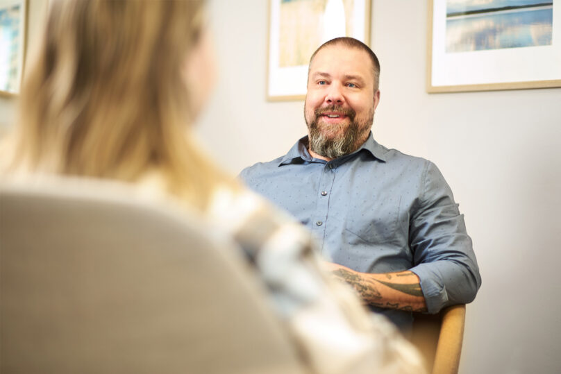 miespsykiatri juttelee edessään istuvan nuoren naisasiakkaan kanssa