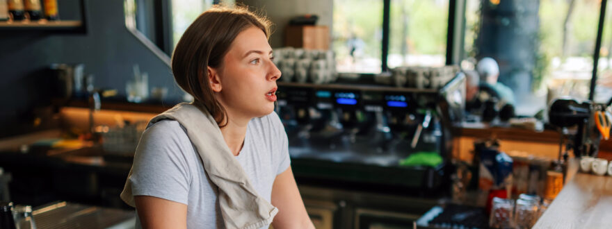 Nuori nainen nojaa baaritiskiin uupuneen oloisena.