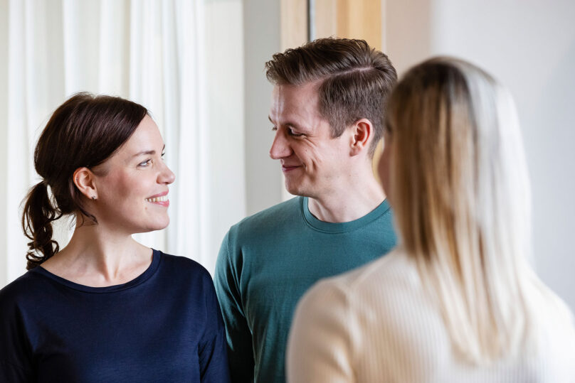 nainen ja mies katsovat toisiaan ja hymyilevat ja terapeutti seisoo vieressa