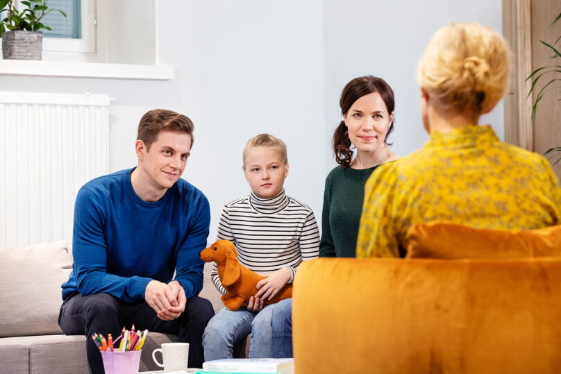 isä, aiti ja tytär keskustelemassa psykoterapeutille sohvalla istumassa