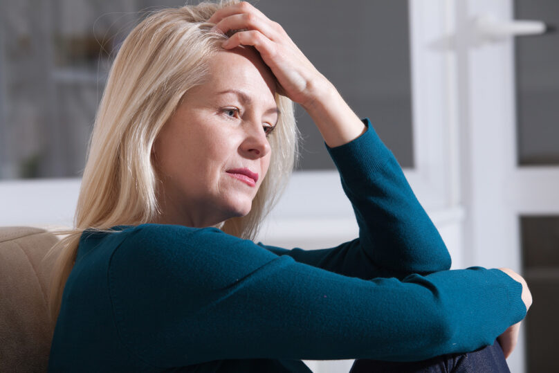 nainen pitaa katta otsalla huolestunut ilme kasvoilla