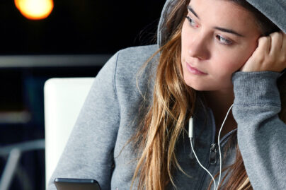 nainen kuuntelee musiikkia kuulokkeet korvissa ja huppu paassa yksin