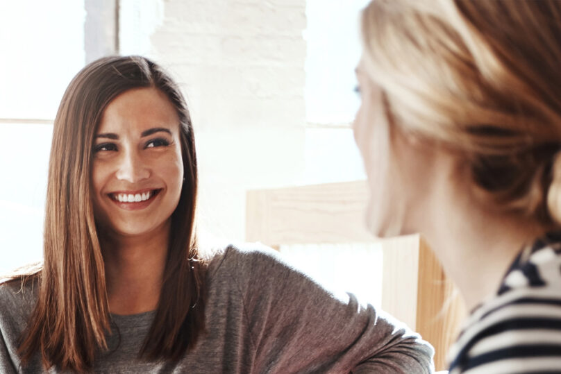 Nainen hymyilee ja keskustelee terapeutin kanssa