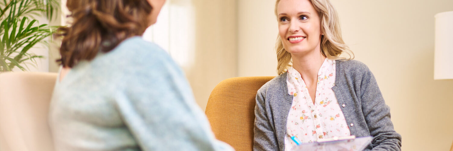Naisasiakas ja naispsykologi istuvat vastakkain ja hymyilevät.