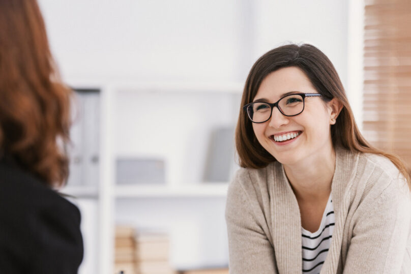 Nainen hymyilee ja keskustelee psykologin kanssa.