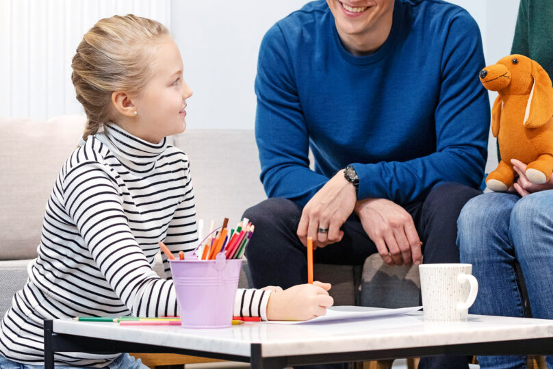 Tytär, isä ja äiti ovat perheterapiassa sohvapöydän äärellä.