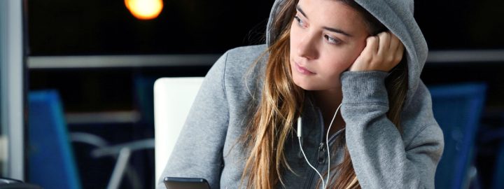 nainen kuuntelee musiikkia kuulokkeet korvissa ja huppu paassa yksin