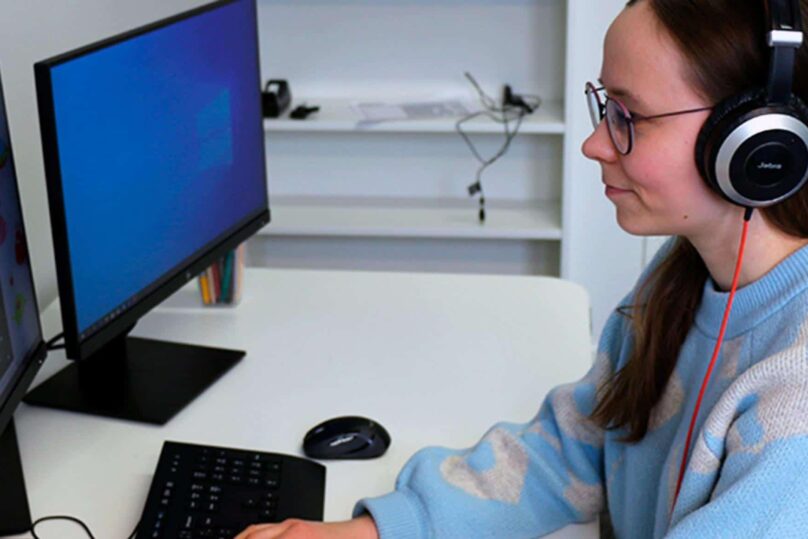 nainen kuulokkeet päässä tietokoneella