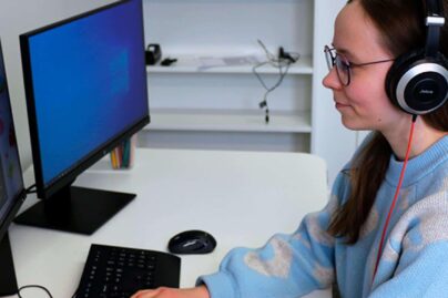 nainen kuulokkeet päässä tietokoneella