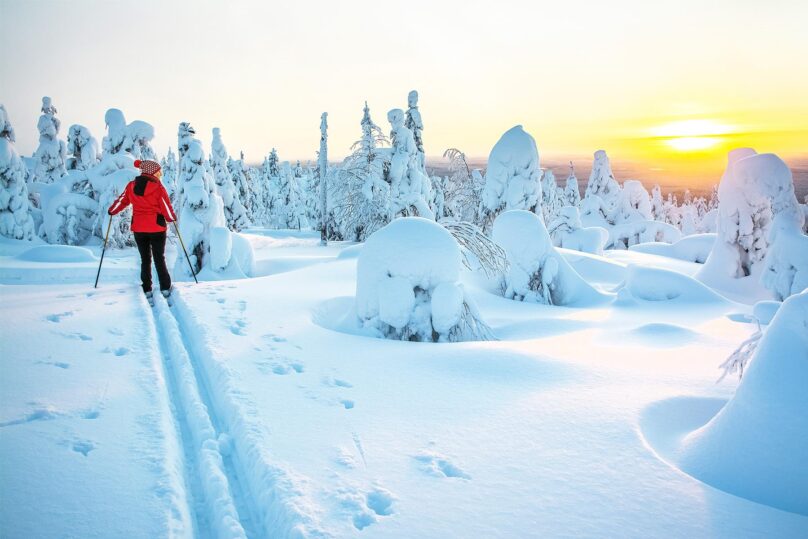 nainen hiihtamassa auringonlaskussa