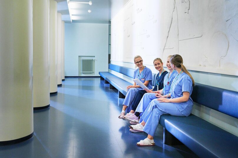 hoitajat istuvat kaytavan penkilla