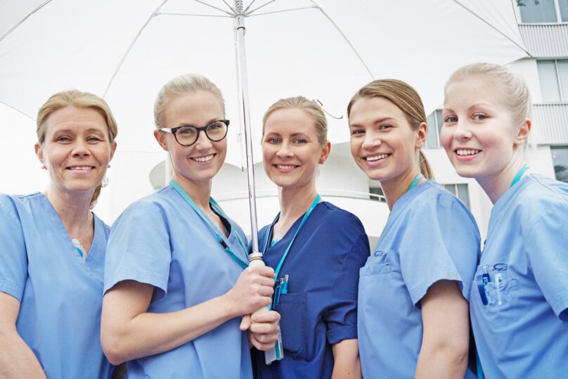 terveysalan tyontekijat hymyilevat ulkona