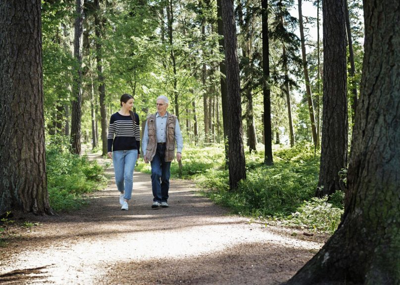 Nainen ja vanhempi mies kävelemässä metsässä.