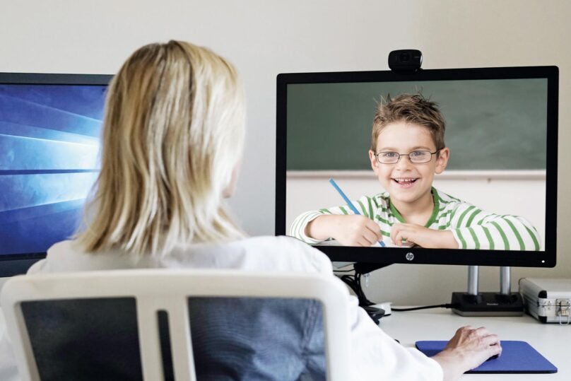 terapeutti nainen toimistolla ja lapsi nakyy tietokoneen ruudulta etayhteyden kautta