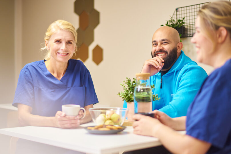 Hoitajat istuvat kahvihuoneessa ja nauravat.