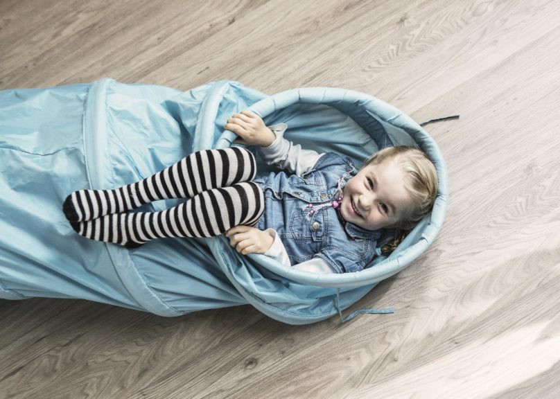 Tyttö hymyilee leikkiputkessa Lasten toimintaterapiassa.