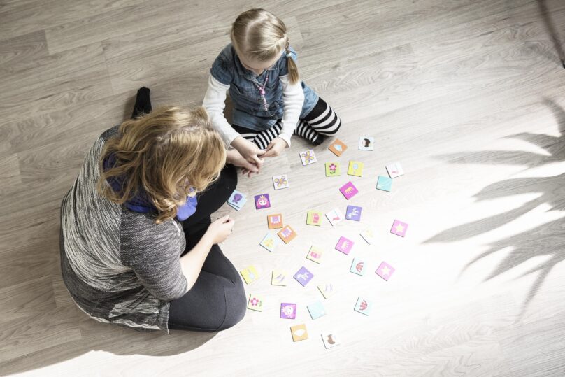 Tyttö ja Coronarian toimintaterapeutti pelaavat yhdessä muistipeliä.
