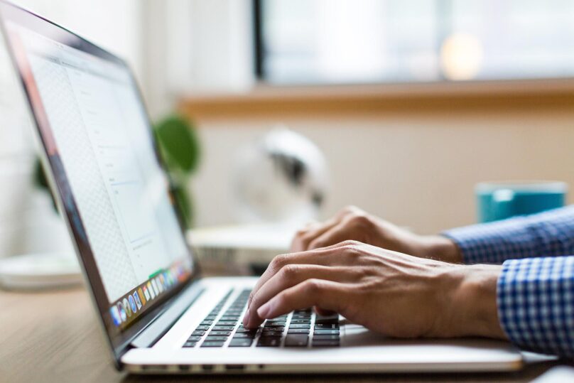 Kädet kirjoittamassa kannettavalla tietokoneella.