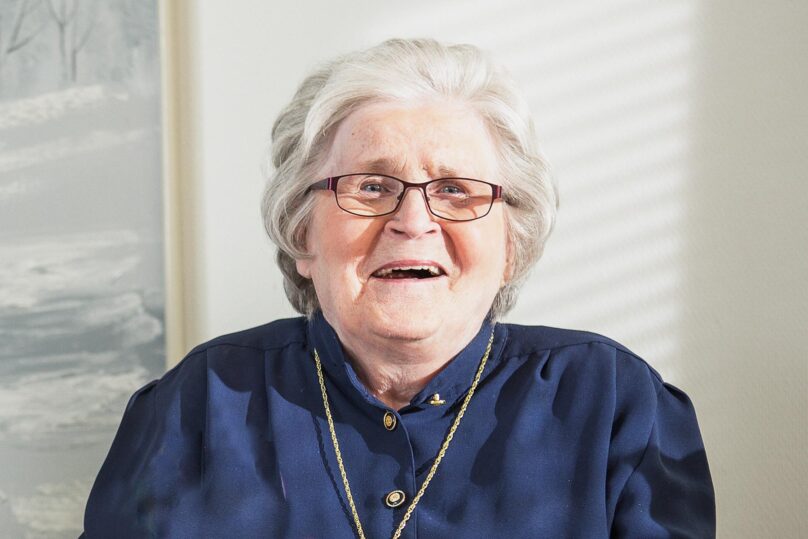 Iäkas nainen hymyilee.